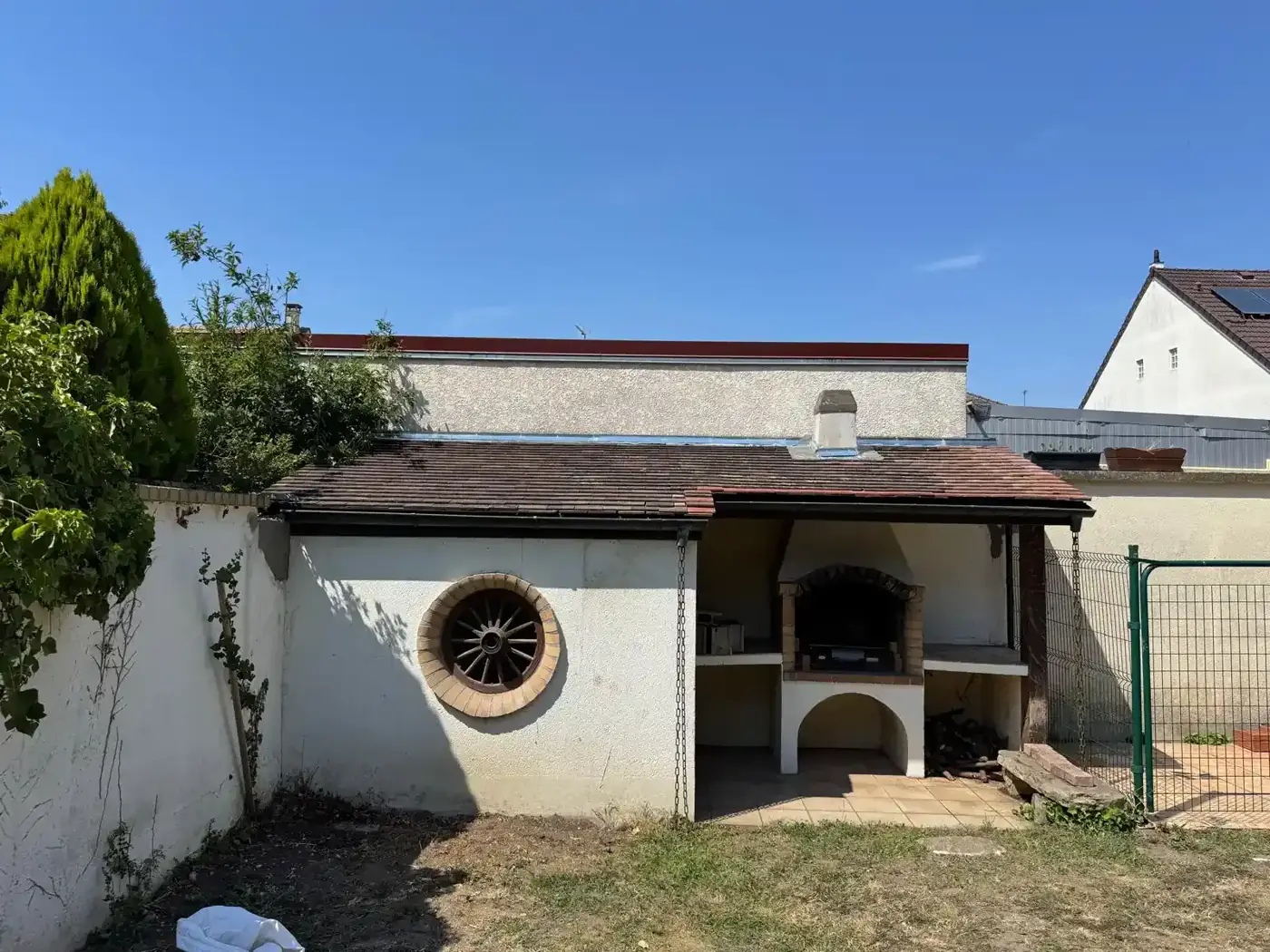 Abri barbecue à Gagny avant travaux : toiture affaissée, tuiles ondulées et végétation au pied des murs