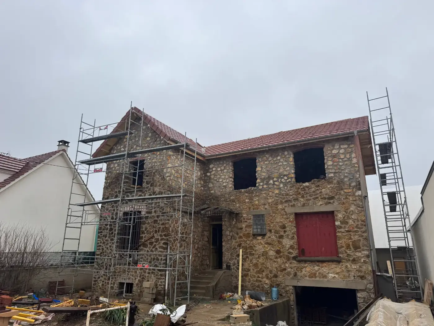 Maison en meulière à Neuilly-sur-Marne avec charpente et couverture en tuiles neuves, échafaudage en place