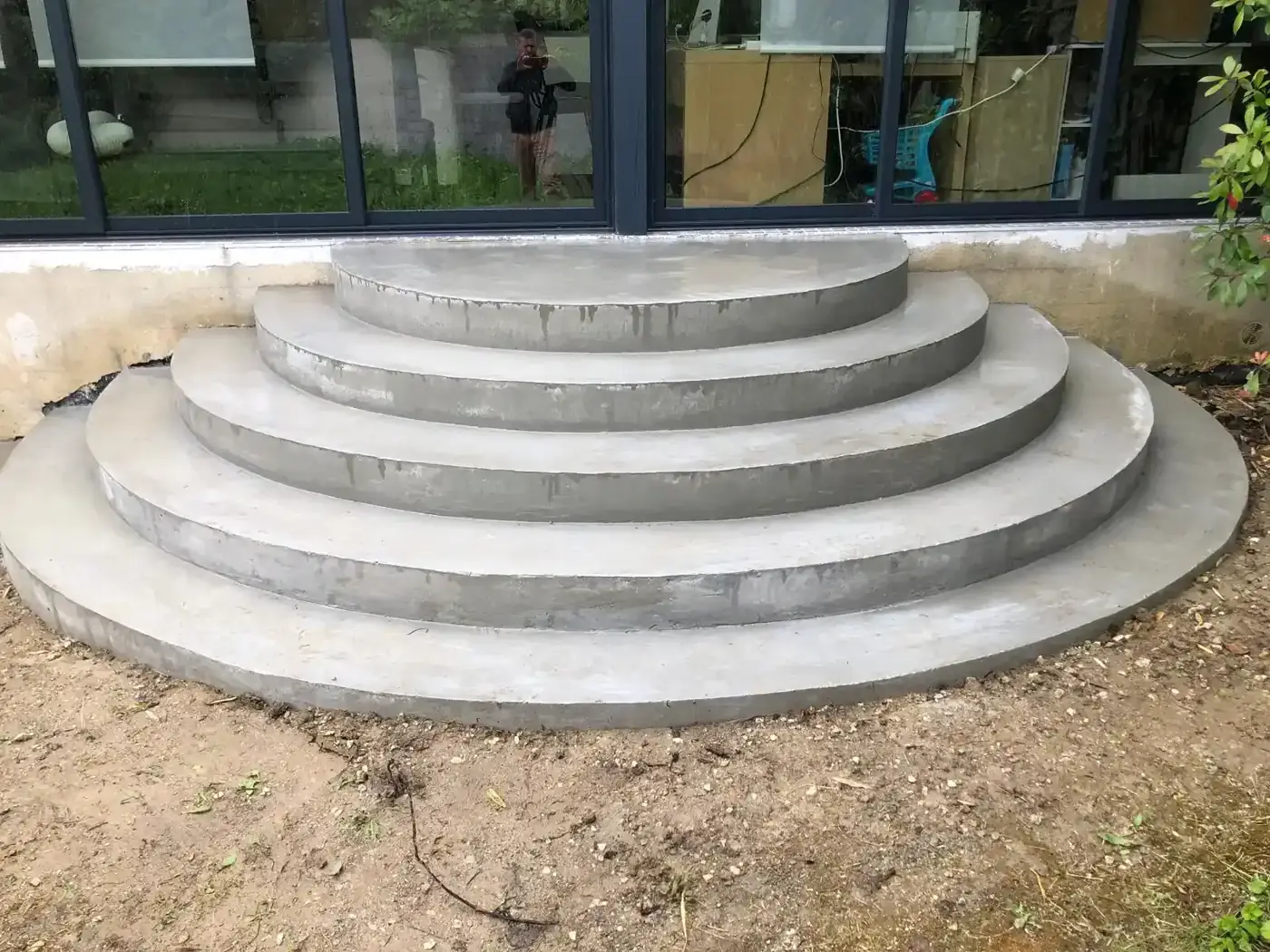Escalier béton en demi-cercle de quatre marches coulé devant une baie vitrée à Chelles, après décoffrage
