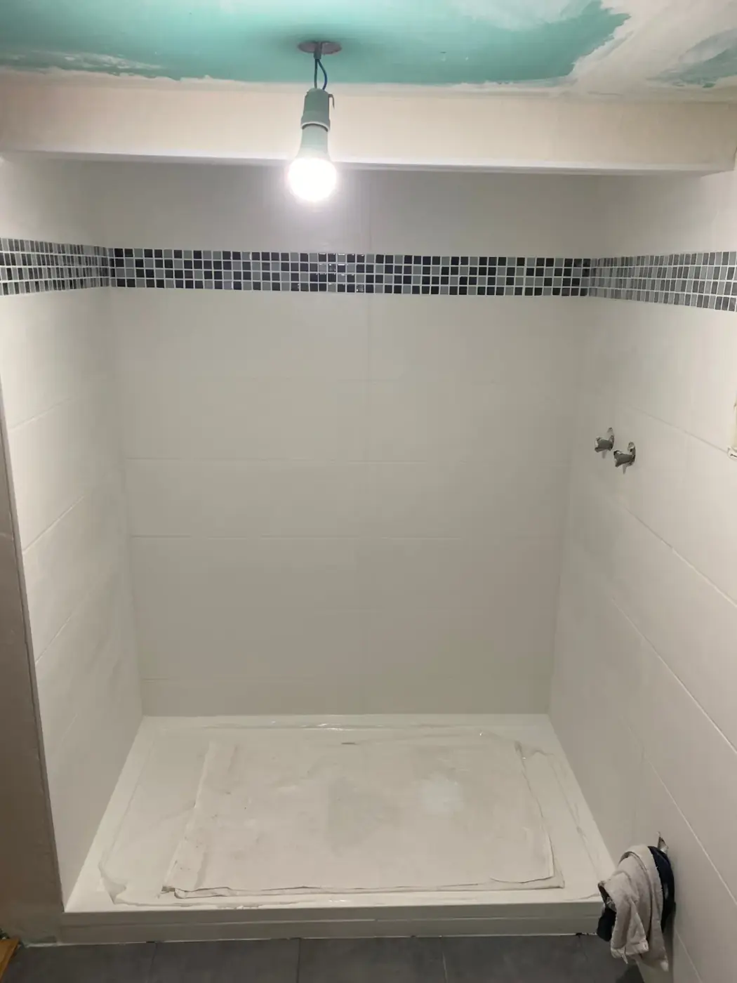Salle d'eau au Raincy en cours de chantier : douche carrelée et frise mosaïque posée