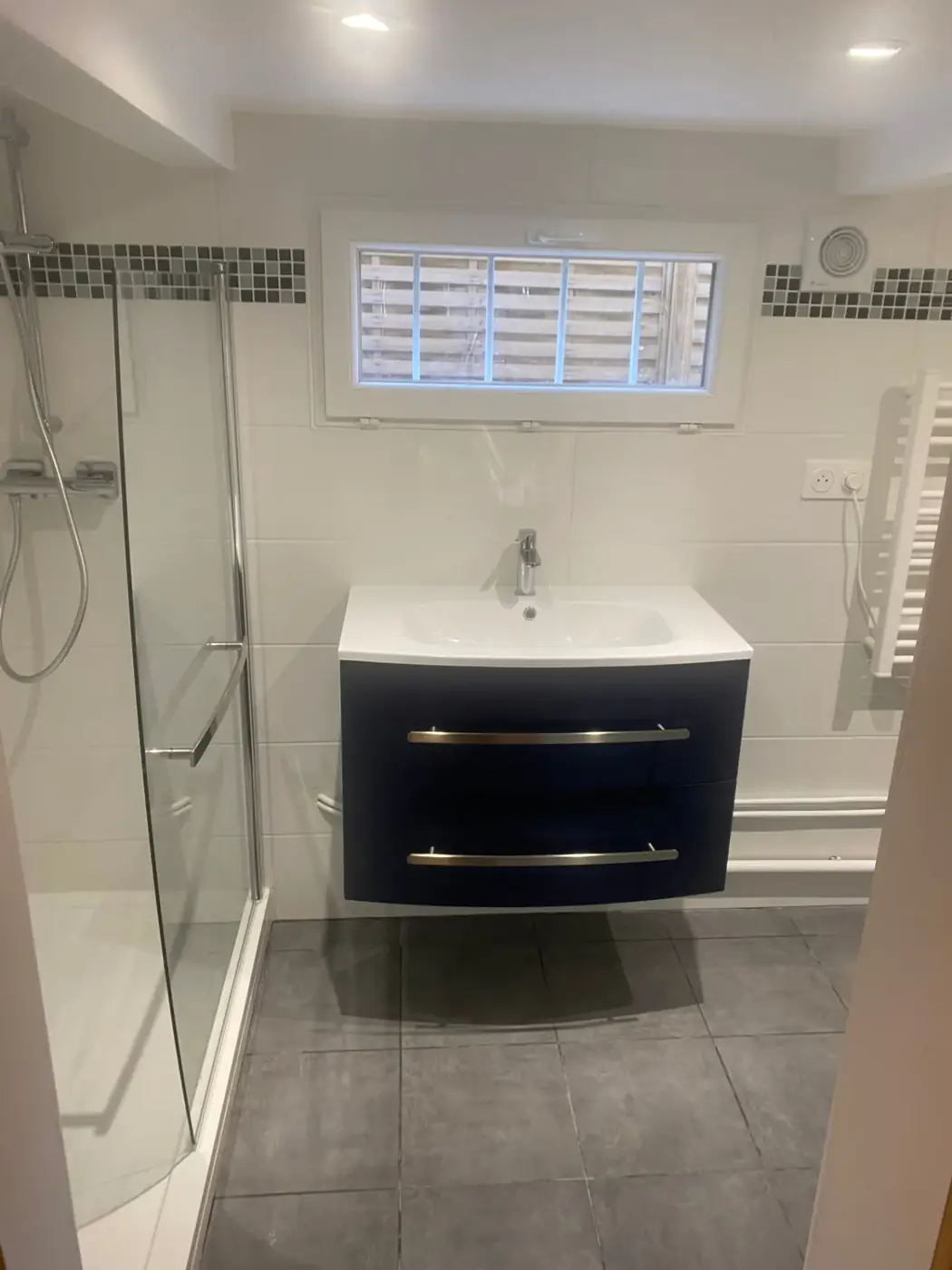Salle d'eau aménagée au Raincy : meuble vasque suspendu, douche à l'italienne et faïence claire