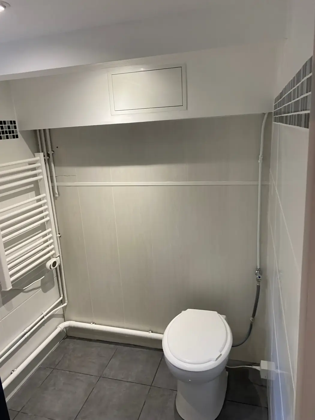Coin toilettes de la salle d'eau au Raincy : sèche-serviettes et faïence claire