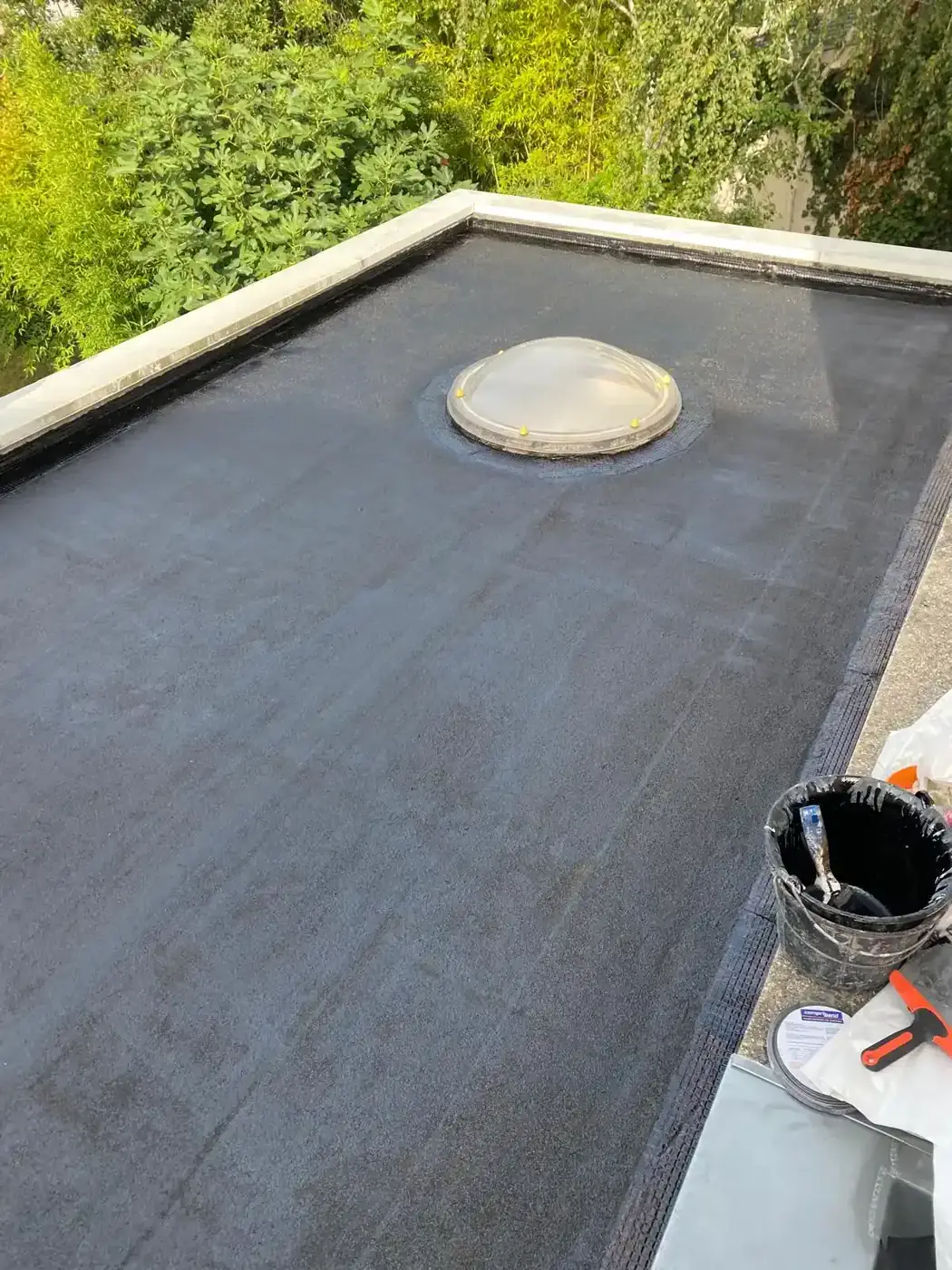Application de l'étanchéité liquide noire sur le support de la terrasse à Colombes, avant pose des dalles