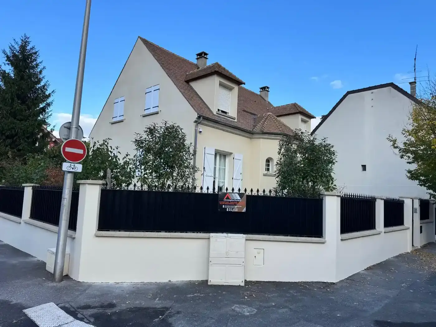 Vue d'ensemble du pavillon à Colombes après les travaux, avec le panneau de chantier COUVERTURE IDF sur la clôture