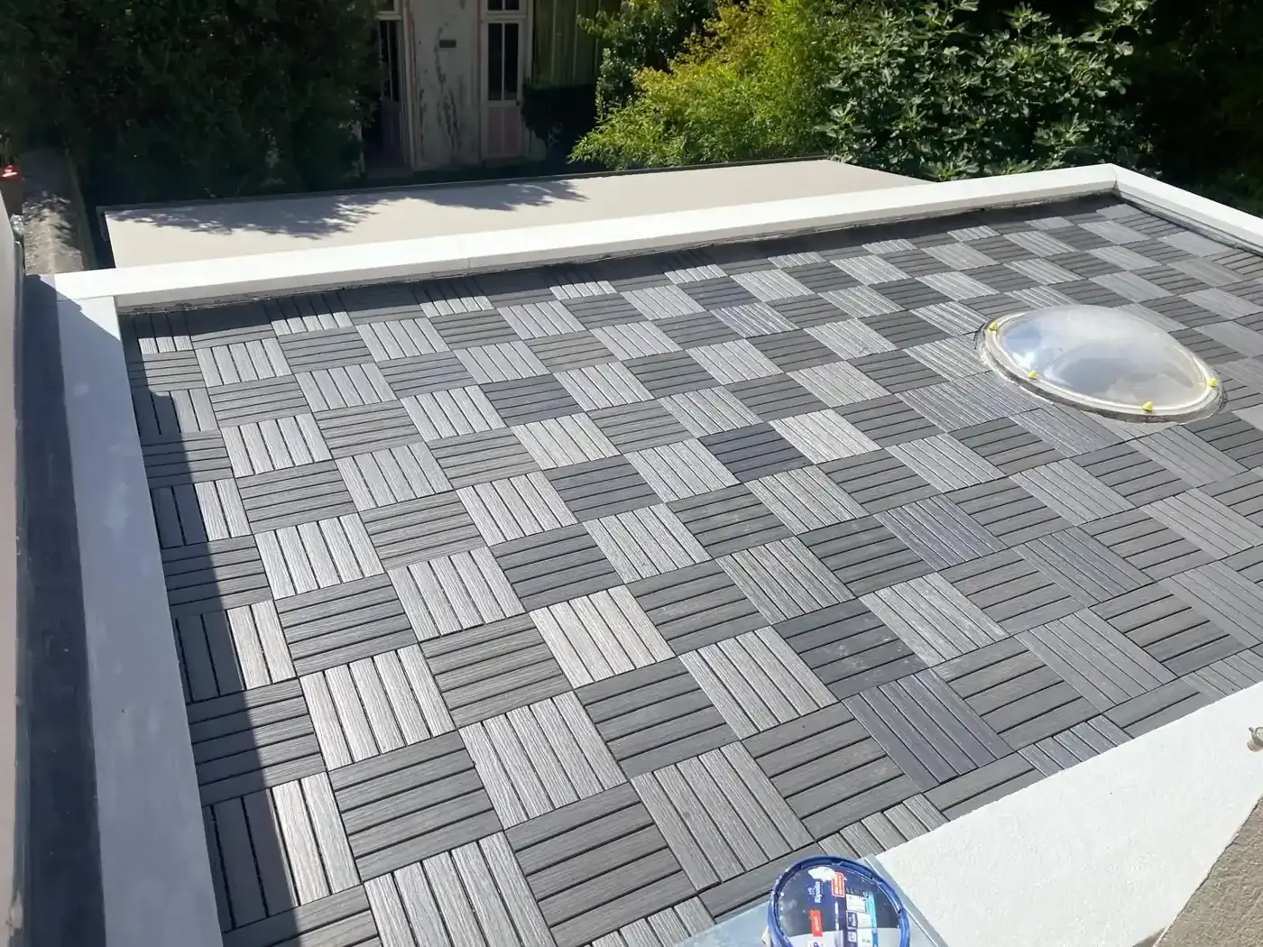 Terrasse sur toit plat rénovée à Colombes avec dalles composite grises posées en damier autour du puits de lumière
