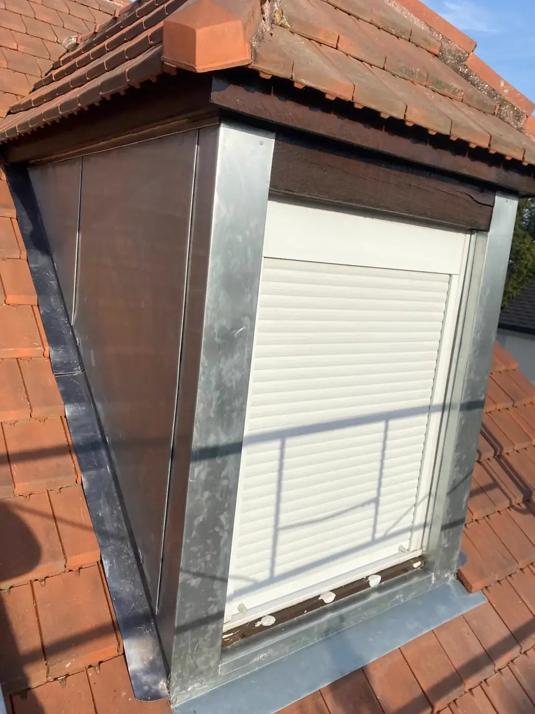 Lucarne chien-assis habillée de zinc laqué blanc avec solin gris anthracite et jouées étanchées aux tuiles à Dammartin-en-Goële